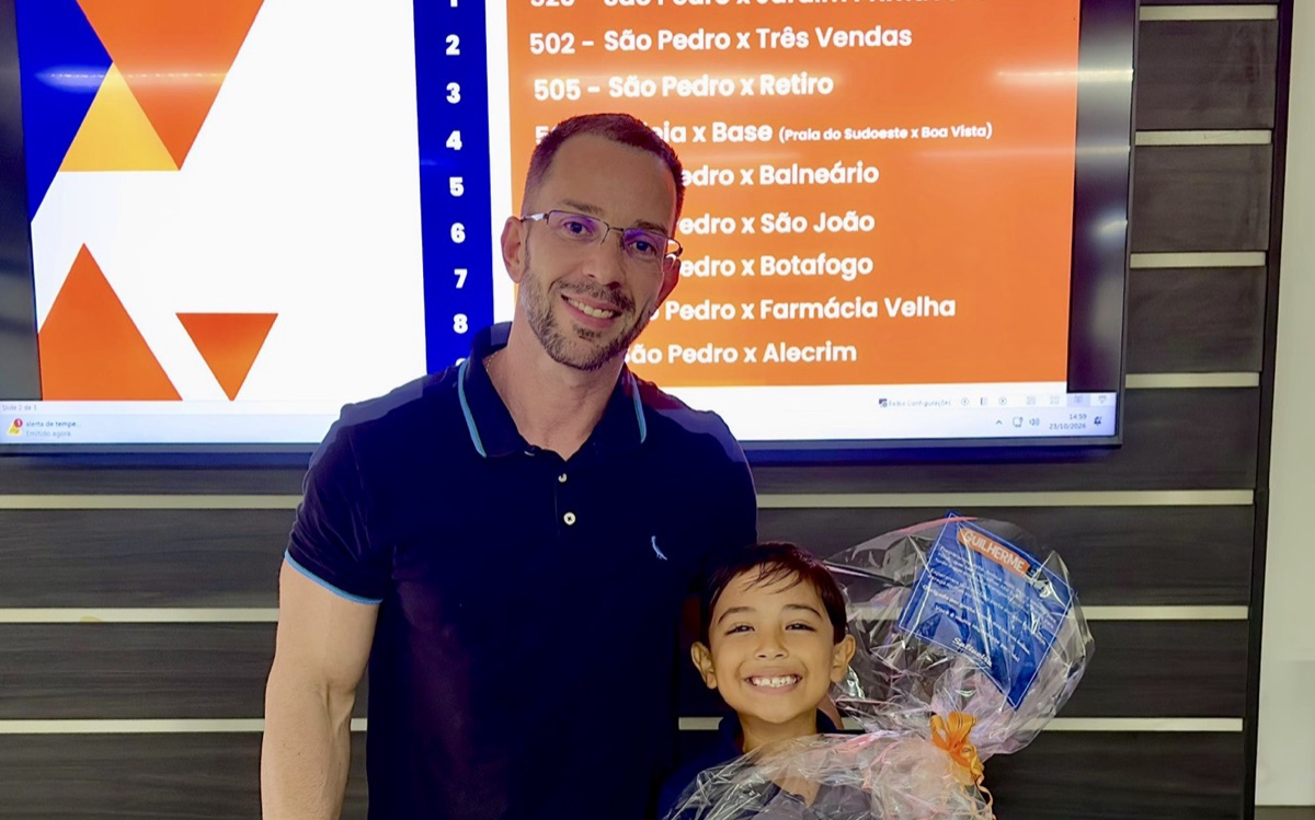 Diego Alves e o Guilherme, com o presente da Salineira, diante da tela do desafio sobre as linhas de ônibus da cidade.